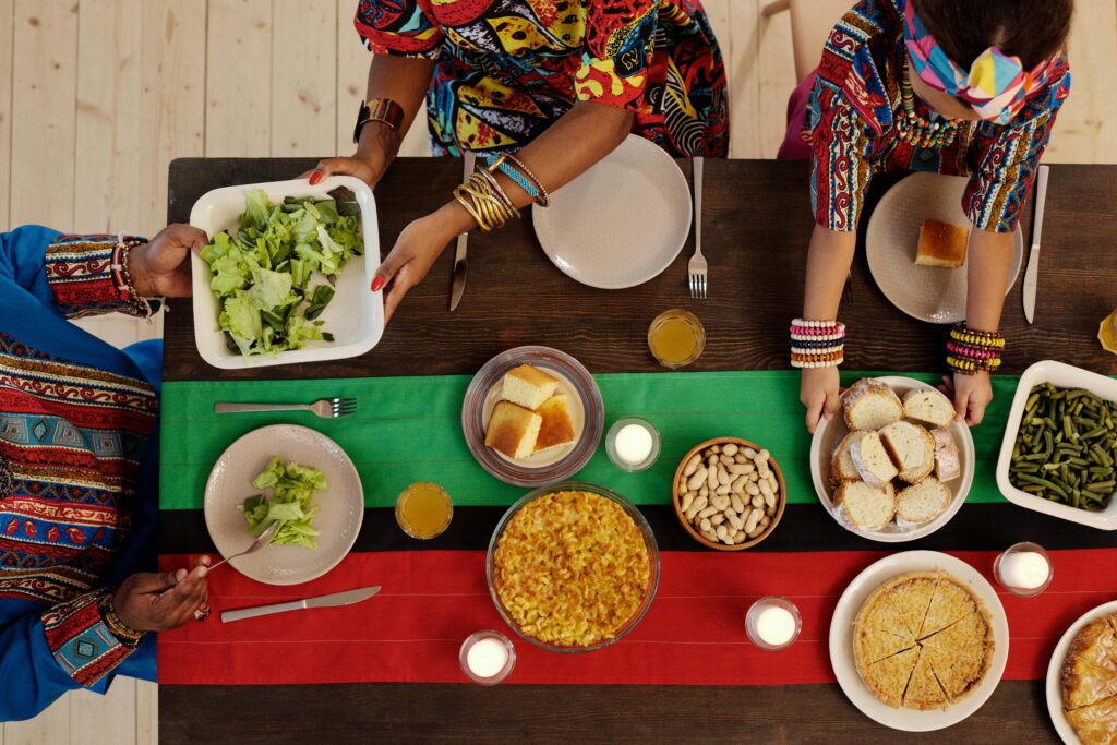 Top view of a family enjoying a Kwanzaa feast with traditional foods and vibrant attire.